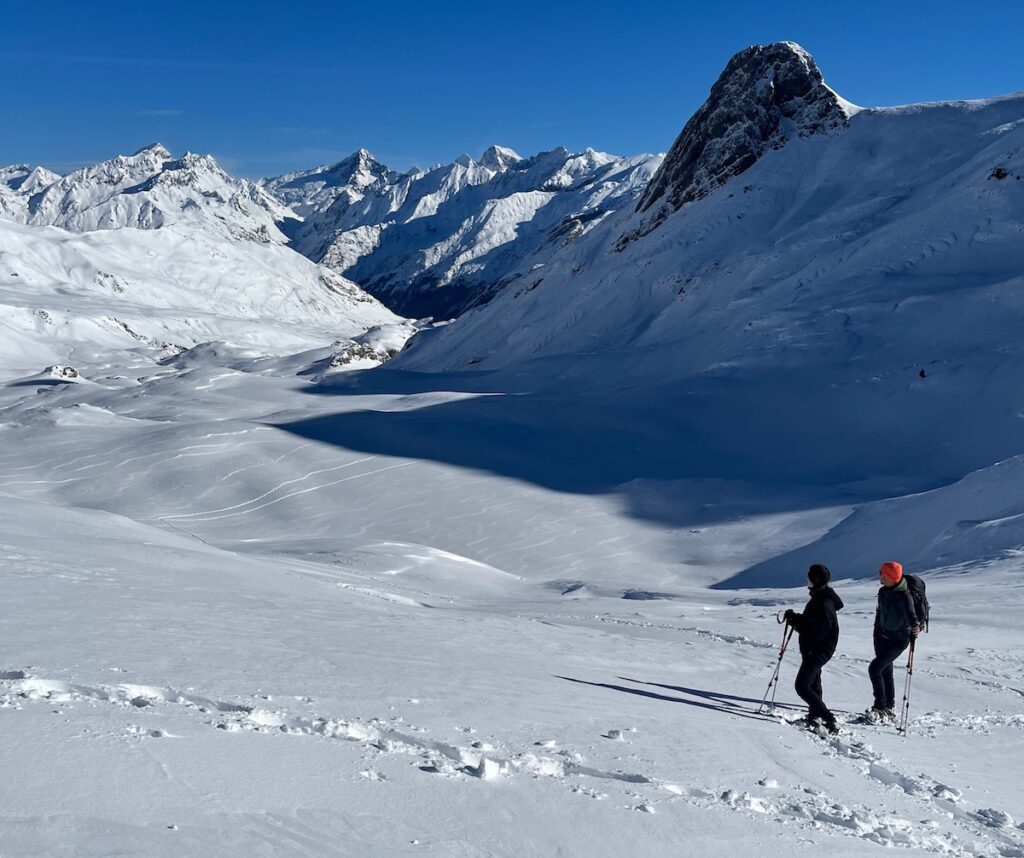 Pareja contemplando las montañas nevadas durante una ascensión con raquetas de nieve en el Valle de Tena