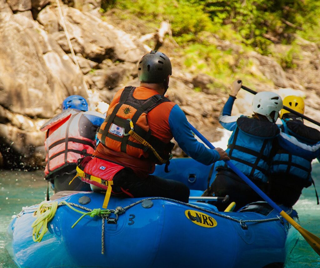 Grupo de amigos disfrutando de un rápido en balsa de rafting por el río Ara, la actividad de aventura estrella en primavera cerca de Ordesa.